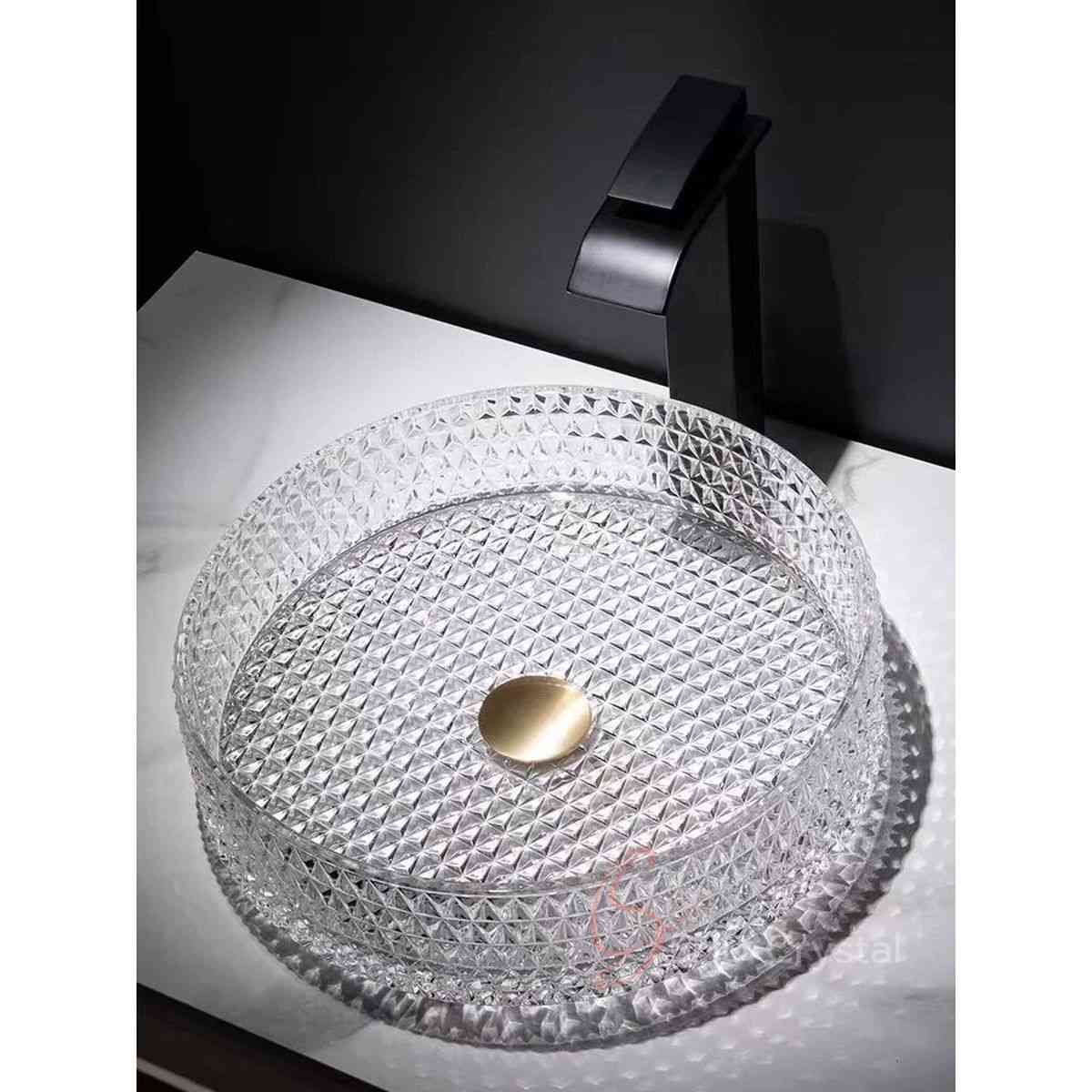 This Prism Round Crystal Washbasin-Clear features a sculptural round vessel silhouette defined by dense prism-like faceted crystal detailing across the entire basin surface. Its transparent crystal construction amplifies the geometric pattern through strong light refraction, creating a jewel-like visual effect that enhances refined vanity and decorative bathroom interiors.

The wide round vessel form provides generous washing space while maintaining a clean low-profile countertop presence, making it suitable for luxury residential bathrooms, boutique hospitality interiors, and contemporary vanity installations. The symmetrical circular geometry allows the faceted surface pattern to remain visually balanced from every viewing angle.

The basin is manufactured through precision molding to create a consistent geometric prism glass basin structure, allowing the dense faceted texture to be integrated uniformly across the inner wall, outer wall, and base surface. This production method ensures accurate pattern definition, balanced wall thickness, and structural consistency across repeated OEM manufacturing.

Designed for decorative vanity environments, upscale hospitality interiors, and premium architectural bathroom projects, this geometric prism glass basin combines functional performance with crisp geometric elegance. SHD Crystal provides custom crystal washbasin OEM services including texture redevelopment, dimensional modification, color customization, drain adaptation, and bespoke production support for private label and project-based clients.